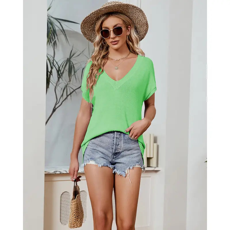 a woman wearing a green top and denim shorts