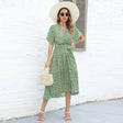 a woman wearing a green floral dress and white hat