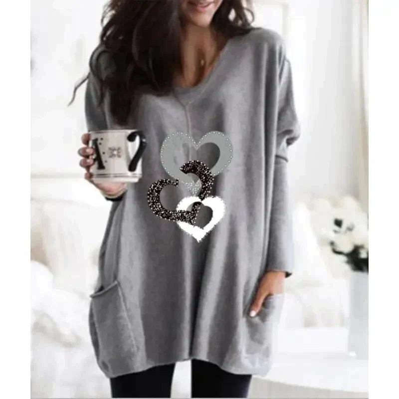 a woman wearing a grey sweater with a heart on it
