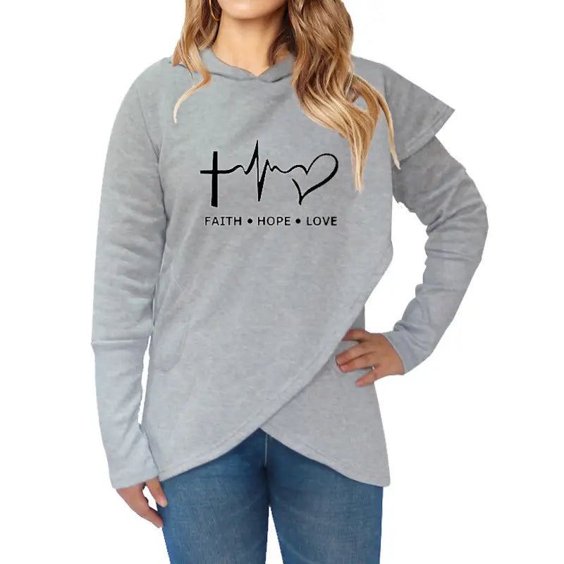 a woman wearing a grey sweatshirt with a heart and cross on it