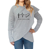 a woman wearing a grey sweatshirt with a heart and cross on it