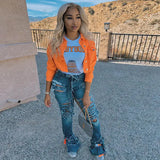 a woman wearing an orange jacket and ripped jeans