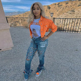 a woman wearing an orange jacket and ripped jeans