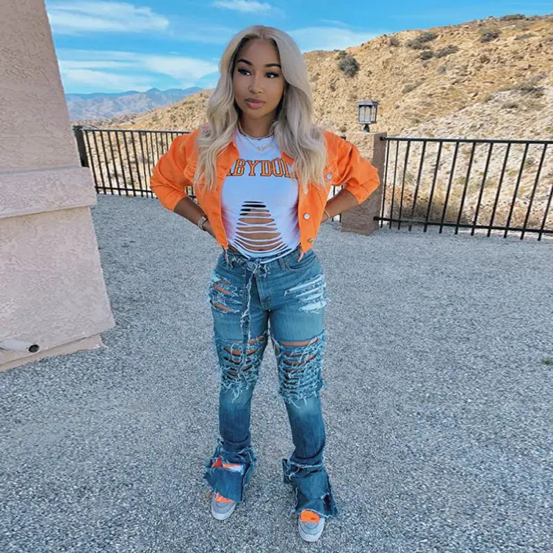 a woman wearing ripped jeans and an orange jacket