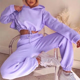 a woman wearing a purple sweatshirt and sweat pants