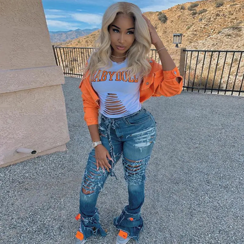 a woman wearing ripped jeans and an orange jacket
