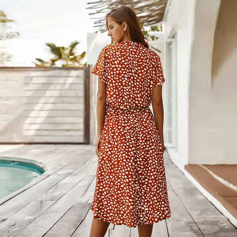 a woman standing on a deck wearing a red and white polka print dress