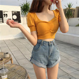 a woman wearing a yellow crop top and denim shorts