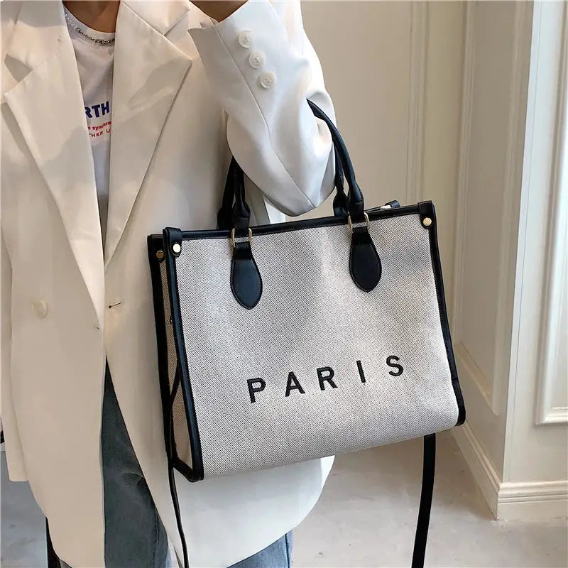 a woman holding a white and black bag with the word paris on it
