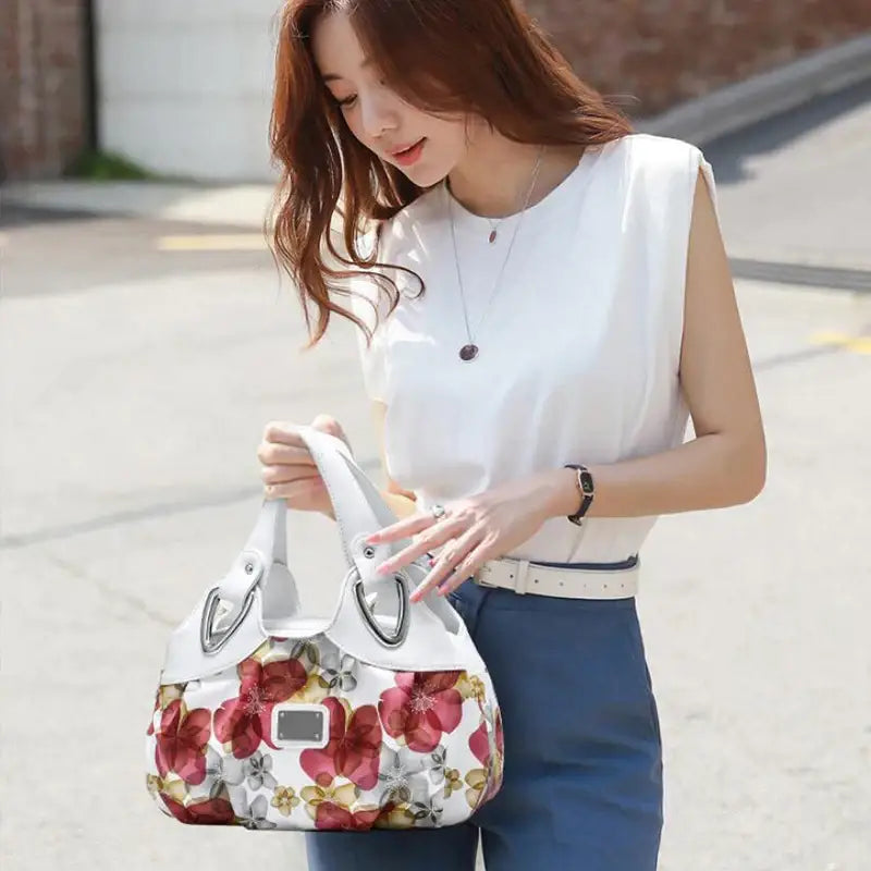 a woman in a white top and blue jeans is holding a white bag