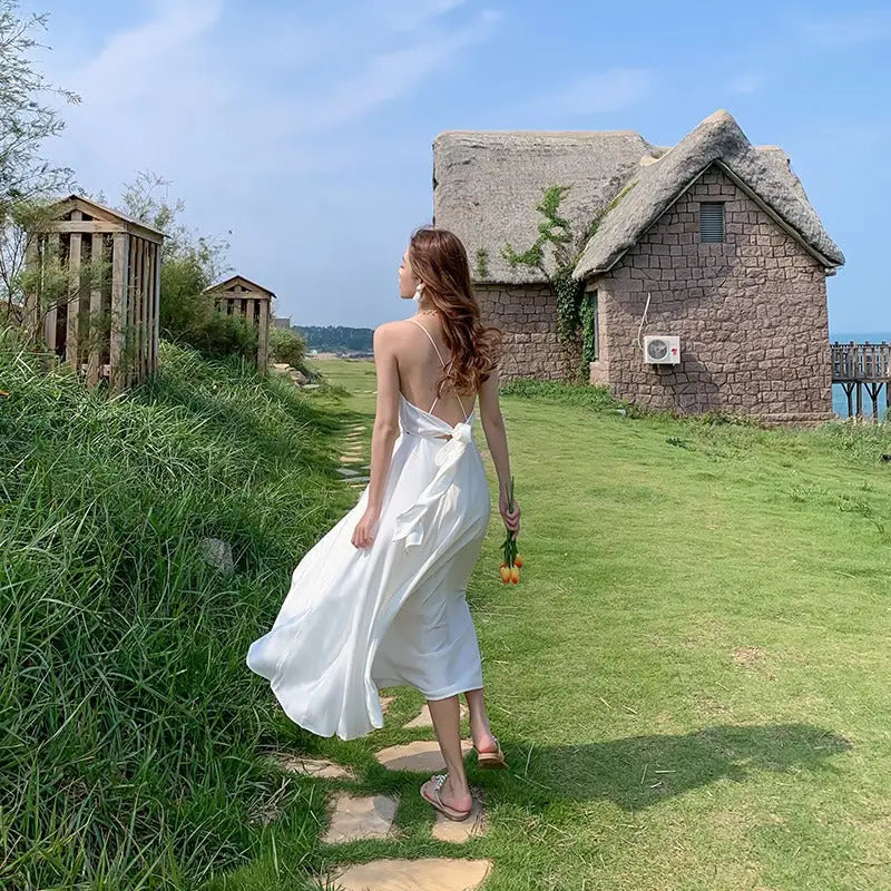 a woman in a white dress walking down a path