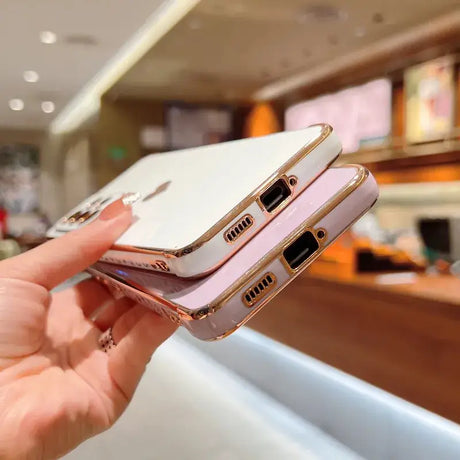 a woman holding a white and gold iphone case