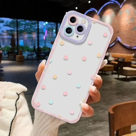 A woman holding up a white iphone case with polka dots