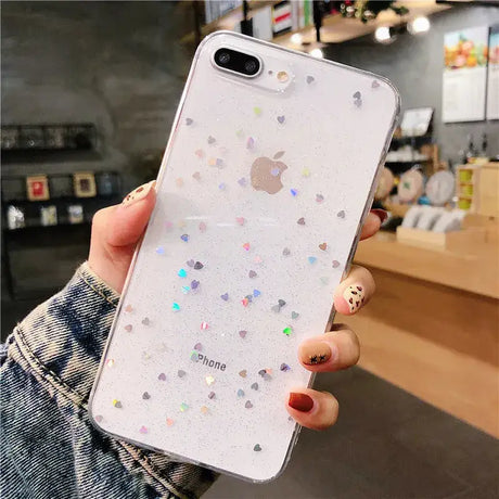 A woman holding a white iphone case with glitter hearts