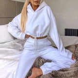 a woman in white outfit sitting on a bed