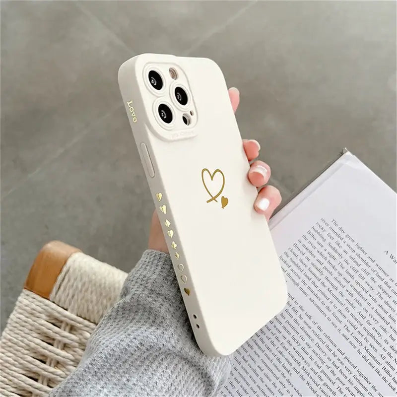 a woman holding a white phone case with a heart