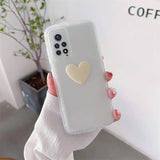 a woman holding a white phone case with a heart on it