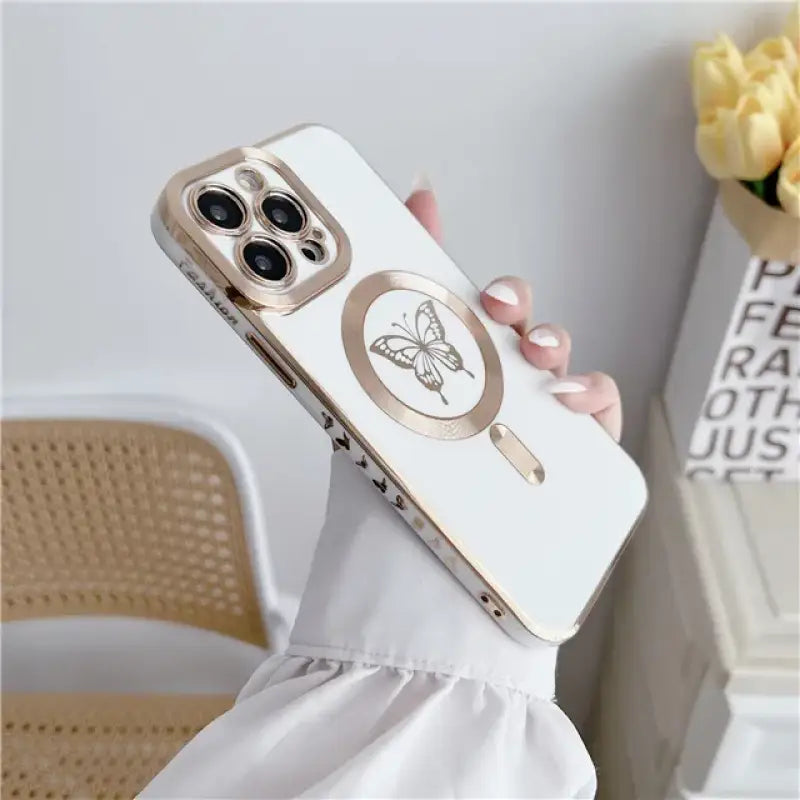 a woman holding a white phone case with a gold butterfly