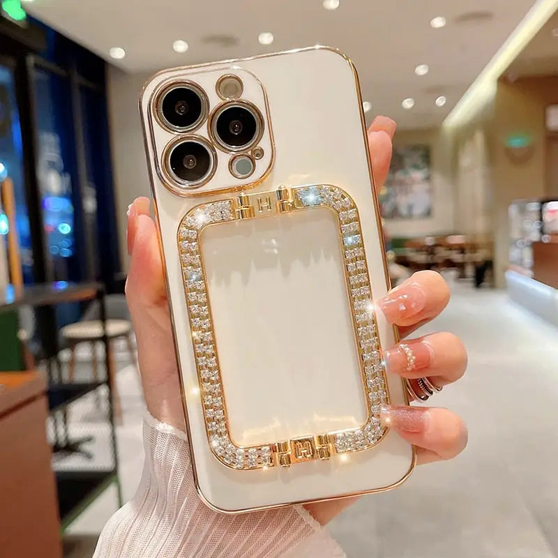 a woman holding a white phone case with gold and diamonds