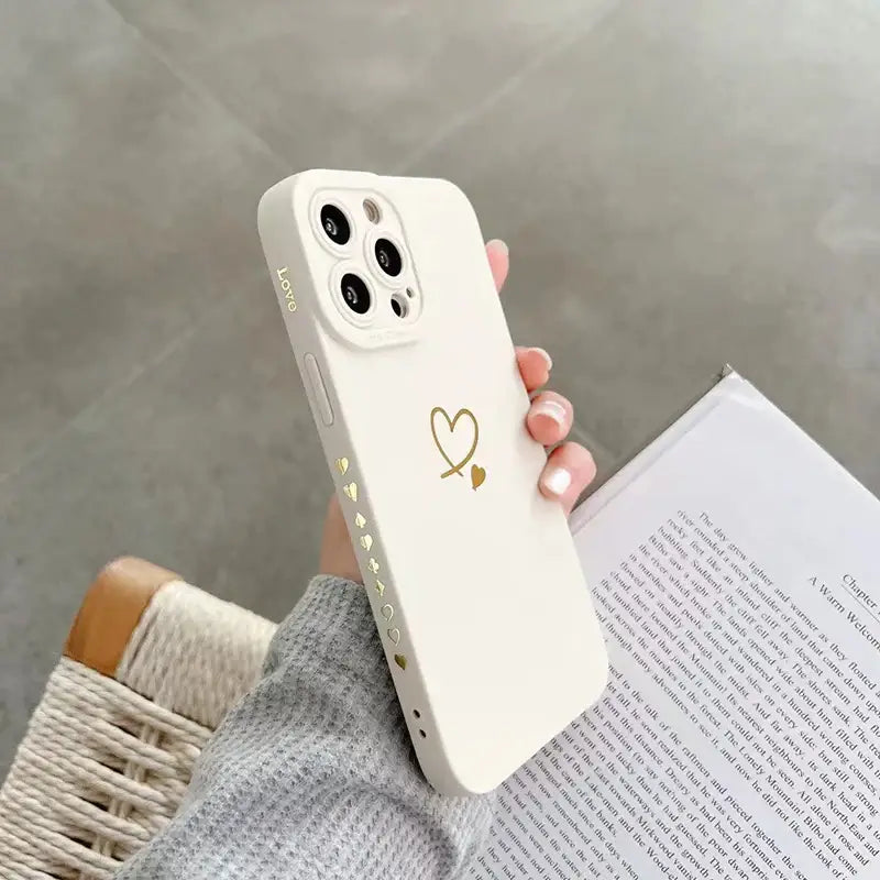 a woman holding a white phone case with a heart on it