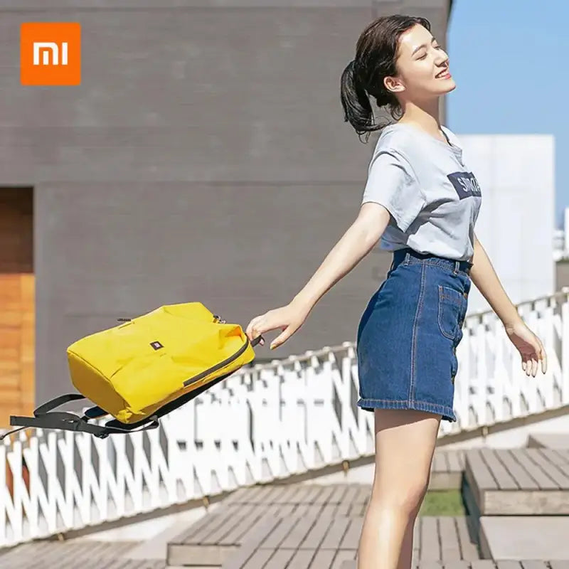 a woman in a white shirt and blue denim skirt holding a yellow bag