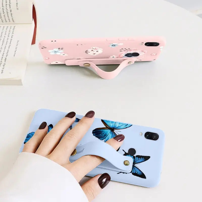 a woman’s hand holding a phone case with a butterfly design