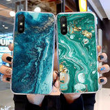a woman holding two iphones with green marble