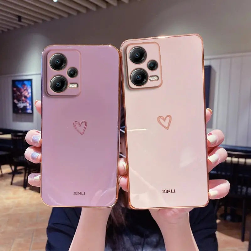 two women holding up their iphones with heart - shaped faces