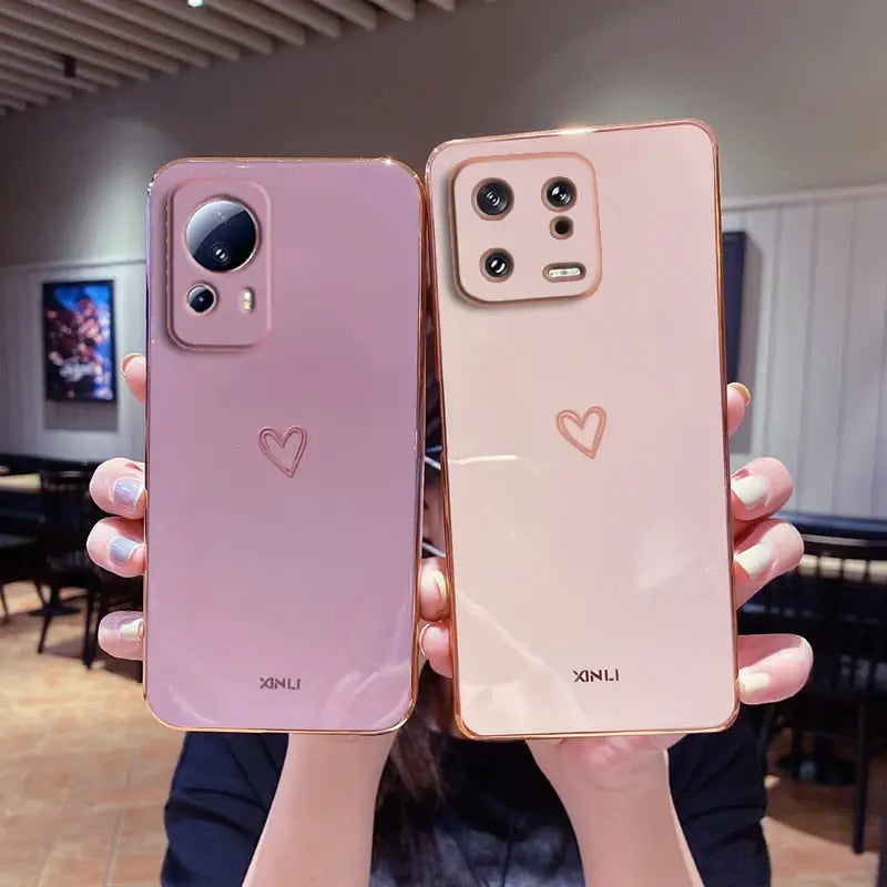 two women holding up their iphones with hearts on them