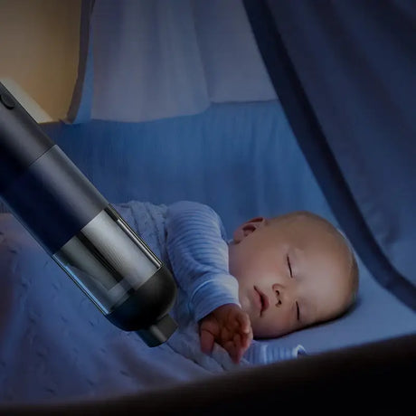 a baby laying in a bed with a vacuum