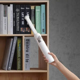 a hand holding a white light bulb over a book shelf