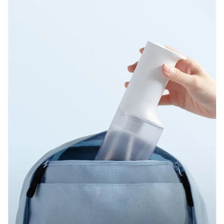 a person putting a white paper in a blue backpack