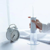 a person holding a toothbrush next to a clock