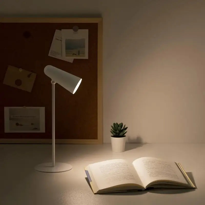 a lamp on a table next to an open book