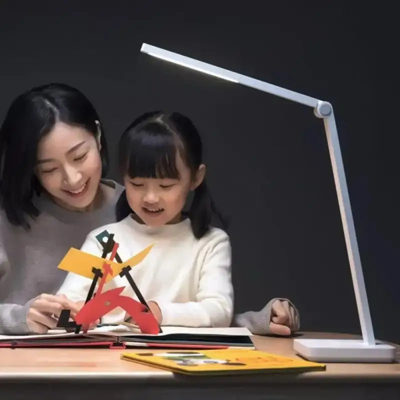 a woman and child are sitting at a table with a laptop