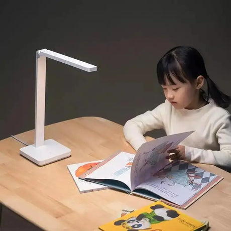 a girl sitting at a table reading a book