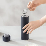 a person putting salt into a black water bottle