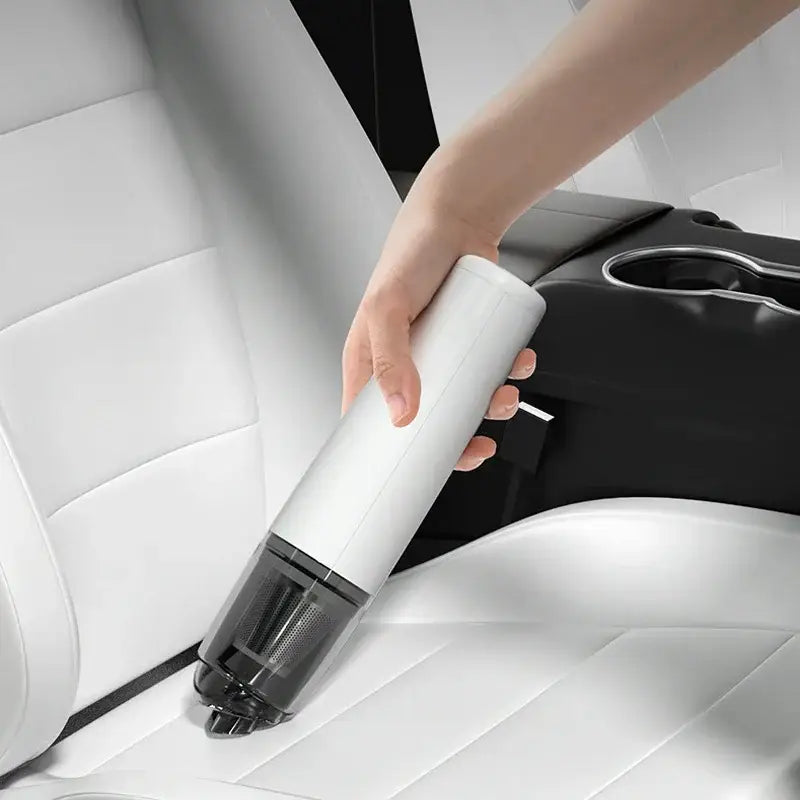 a person cleaning a car seat with a vacuum