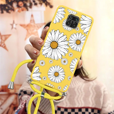 there is a woman holding a phone with a yellow case with white flowers