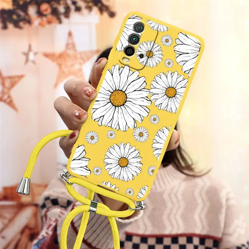 there is a woman holding a phone with a yellow case with white flowers