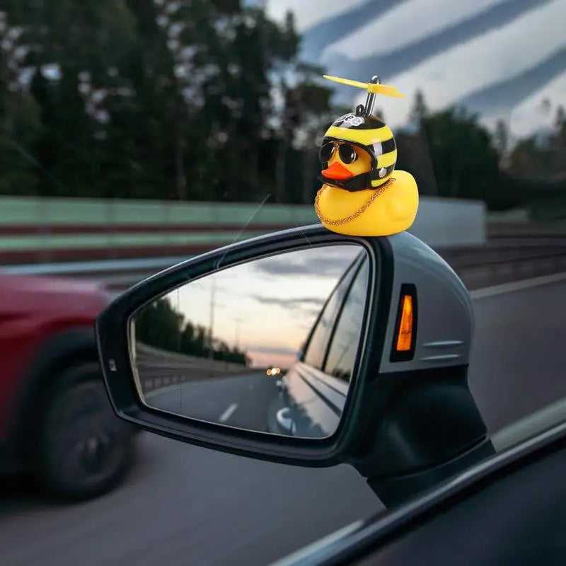 a yellow duck sitting on the side mirror of a car
