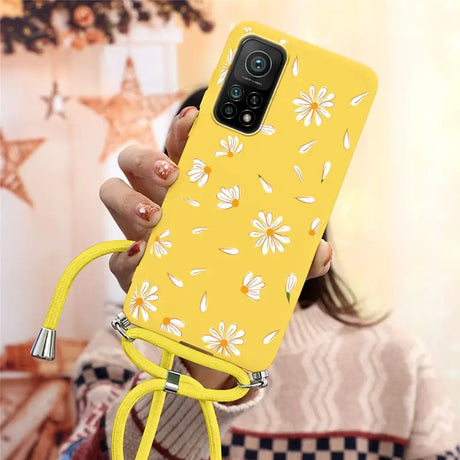 a woman holding a yellow phone case with white flowers on it