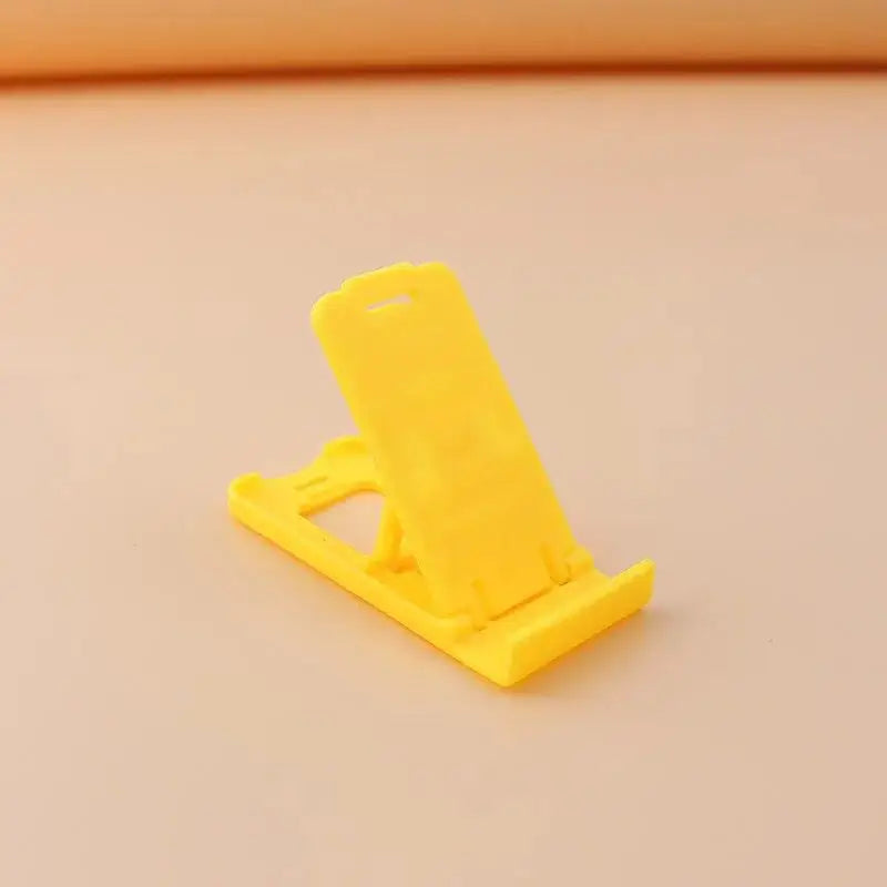 a yellow plastic phone stand on a white surface