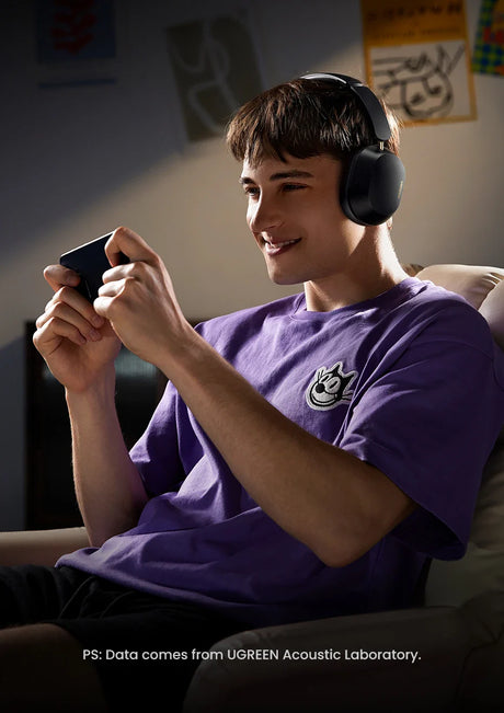 Young person wearing headphones and playing a handheld video game console.