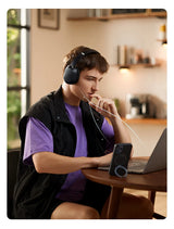 Young person wearing headphones while working on a laptop at a table.