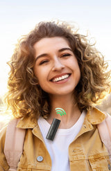 Smiling young woman with curly blonde hair wearing a tan jacket.