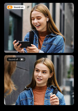 Young woman wearing a denim jacket and orange sweater, smiling while looking at a smartphone.