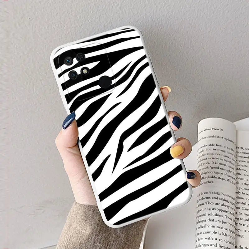 a woman holding a phone case with zebra print
