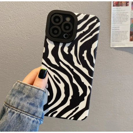 a woman holding a black and white zebra print phone case